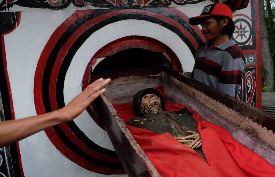 A relative takes the body of the late L Sarongu into his grave or patane in Pangala
